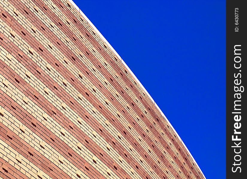 View of modern building with curved architecture against a bright blue sky.