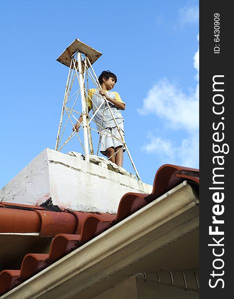 Young child holding on to a tower on the roof of his house. Young child holding on to a tower on the roof of his house.