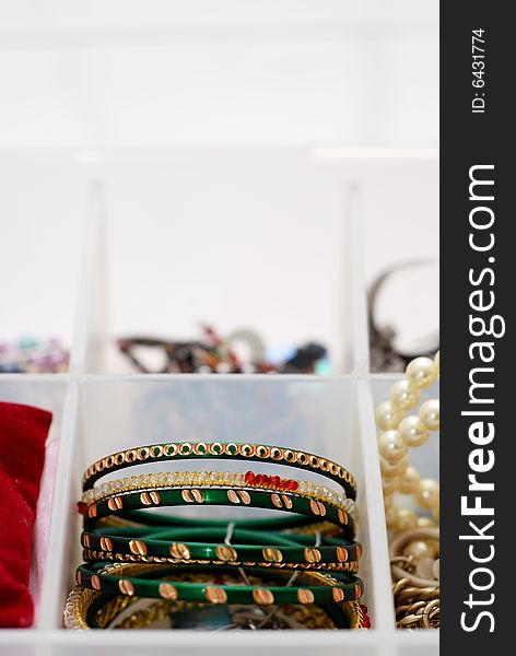 Several green bangles with gold adornments in a plastic white jewelry box. Several green bangles with gold adornments in a plastic white jewelry box