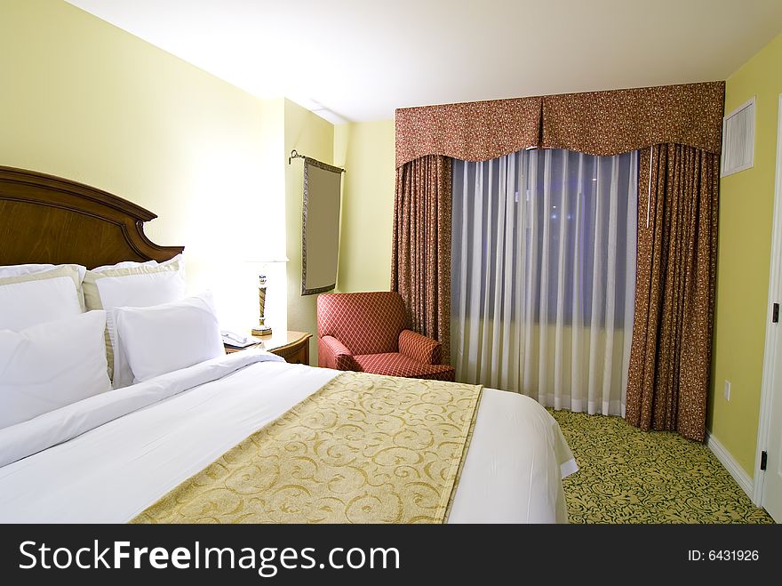 Partial view of bed and chair with curtains and window in background