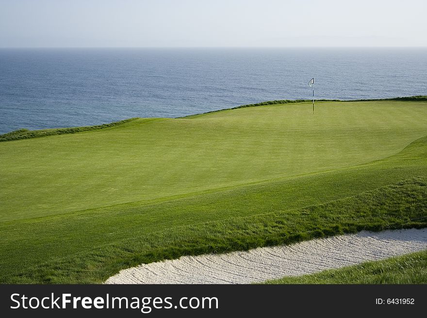 Golf course green and flag overlooking ocean. Golf course green and flag overlooking ocean