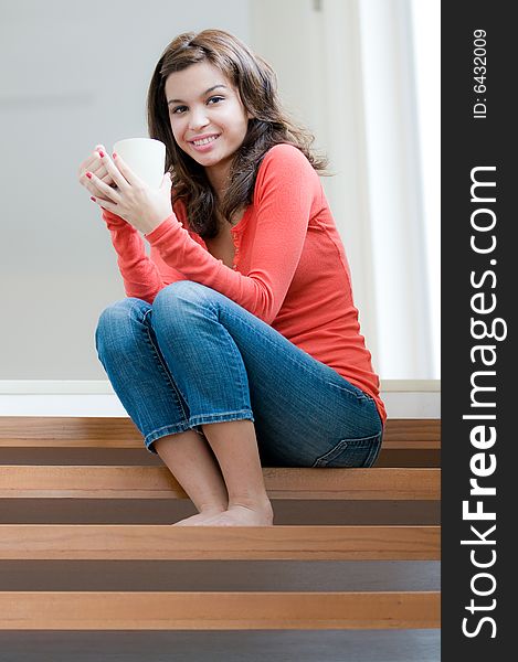 An attractive young woman drinking on the stairs. An attractive young woman drinking on the stairs