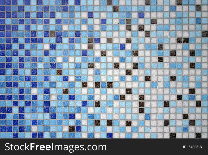 A wall of small mosaic tiling showing a contrast of blue color. A wall of small mosaic tiling showing a contrast of blue color