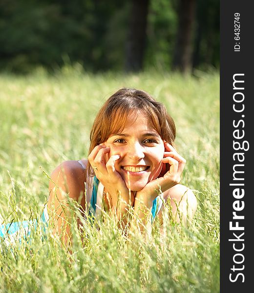 Happy smiling girl lying on the grass