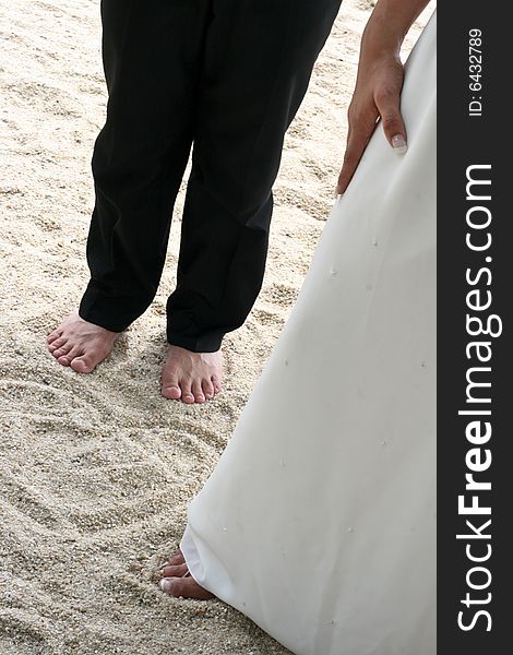 Bride and groom next to a love heart pattern in the sand.