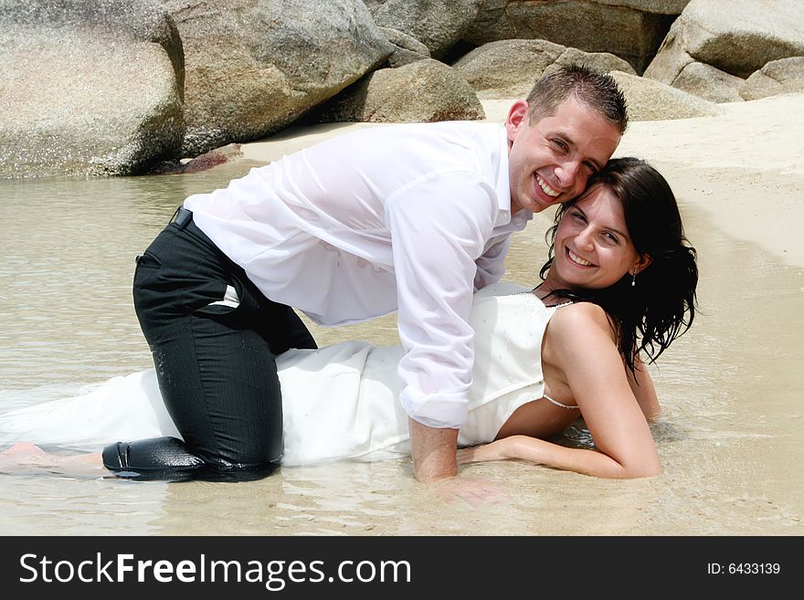 Bride and groom playing in the ocean.