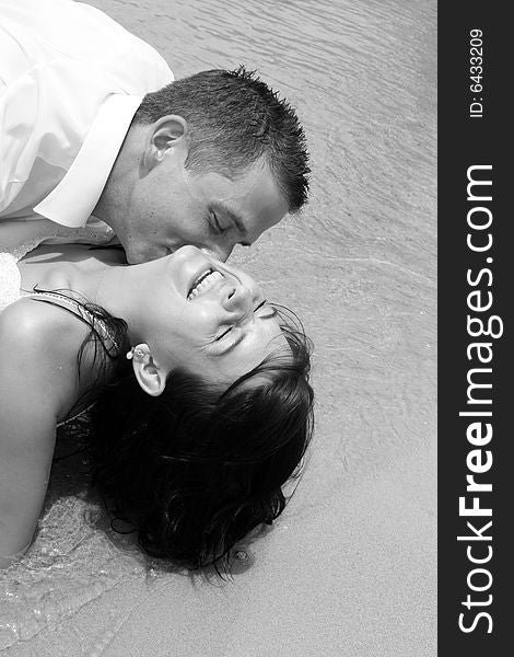 Bride and groom playing in the water at the beach.