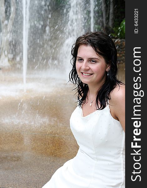 Beautiful young bride next to a waterfall on her wedding day.