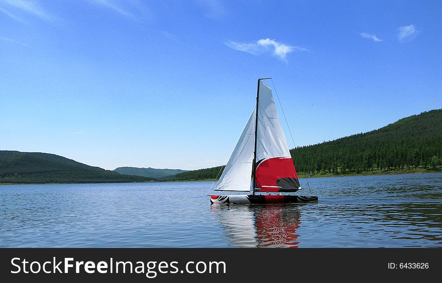 Model yacht being sailed upon a lake. Model yacht being sailed upon a lake.