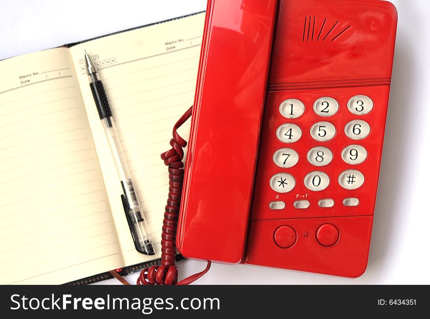 The red plastic telephone set,note book and a ballpen. The red plastic telephone set,note book and a ballpen.