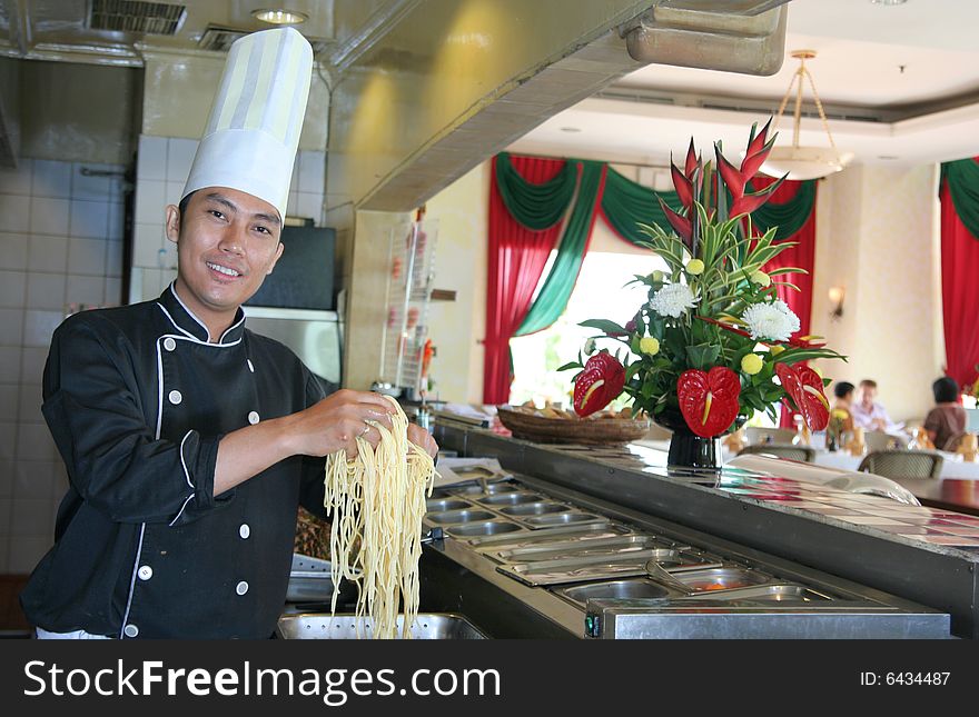 Photograph of chef showing spaghetti in restaurant kitchen