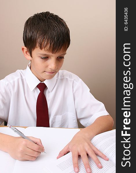 Teenage School boy busy with his homework, wearing uniform