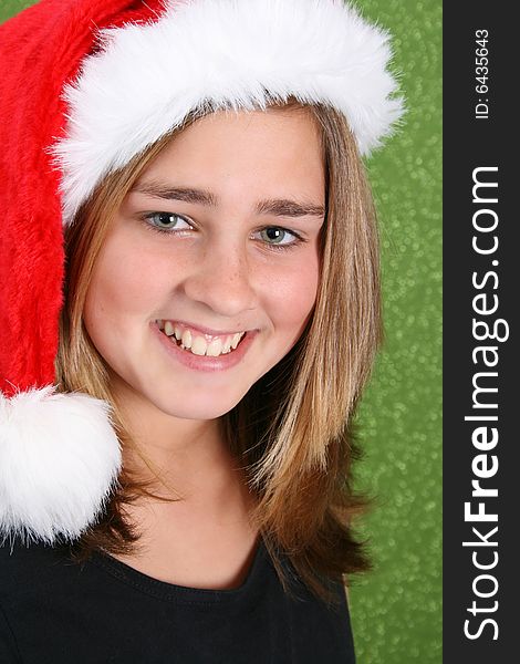 Smiling Teen wearing a christmas hat against a green background. Smiling Teen wearing a christmas hat against a green background