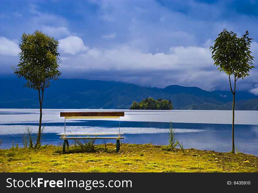 In a quiet lake next to a chair and two trees posed a interesting picture. In a quiet lake next to a chair and two trees posed a interesting picture