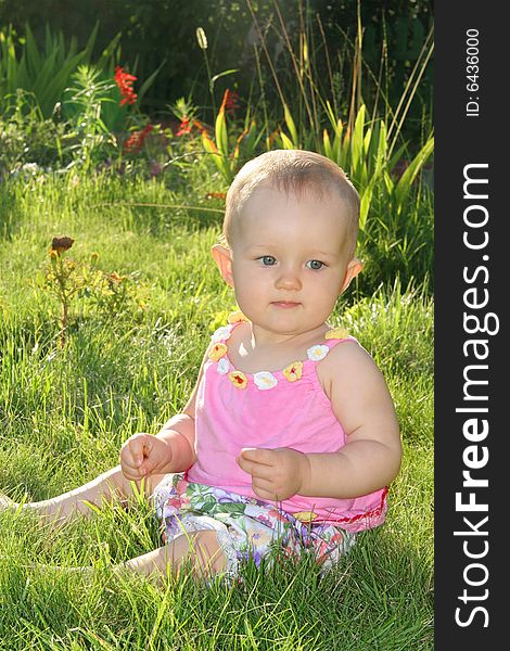 Baby girl sitting on the grass in the sun