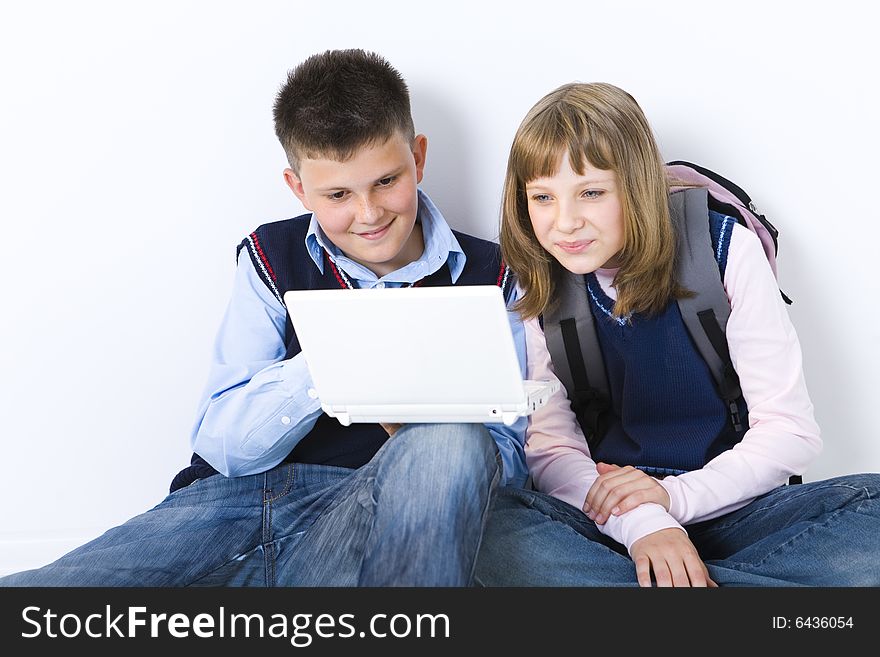 Boy and girl sitting on the floor. Boy showing something to girl on laptop. Front view. Boy and girl sitting on the floor. Boy showing something to girl on laptop. Front view.