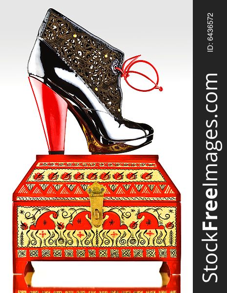 Fancy boot with red heel and laces on decorated jewelery box. Fancy boot with red heel and laces on decorated jewelery box.