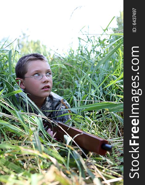 Child in grass with toy rifle looking up into the sky as if hunting birds. Child in grass with toy rifle looking up into the sky as if hunting birds