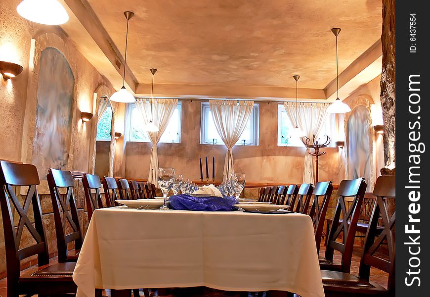 The beautiful romantic dining room with wooden chairs, long table, candlestick and blue decoration in atmospheric light.