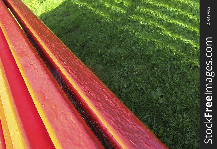 Painted wooden boards and shadow on  green herb in park. Painted wooden boards and shadow on  green herb in park