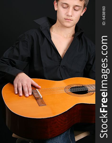 Teenage male in casual attire holding a guitar. FOCUS ON GUITAR by HAND. Teenage male in casual attire holding a guitar. FOCUS ON GUITAR by HAND