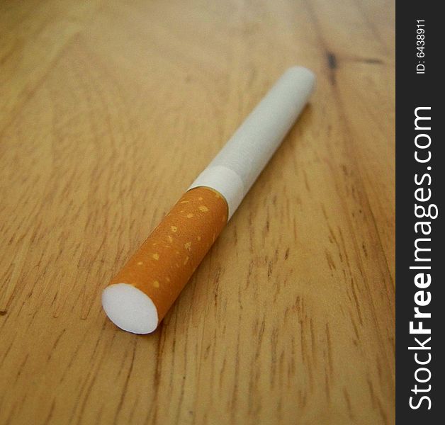 A cigarette on a table, close up. A cigarette on a table, close up