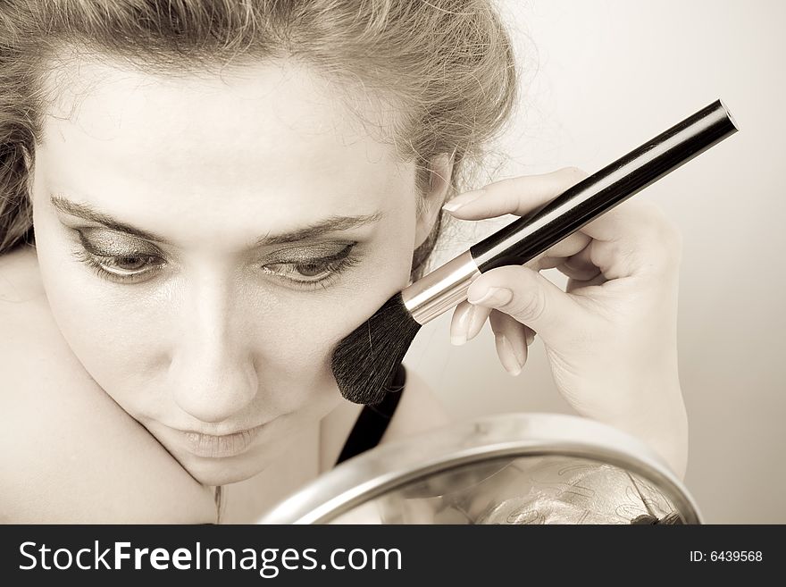 Closeup of woman applying loose powder with thick black brush. Closeup of woman applying loose powder with thick black brush