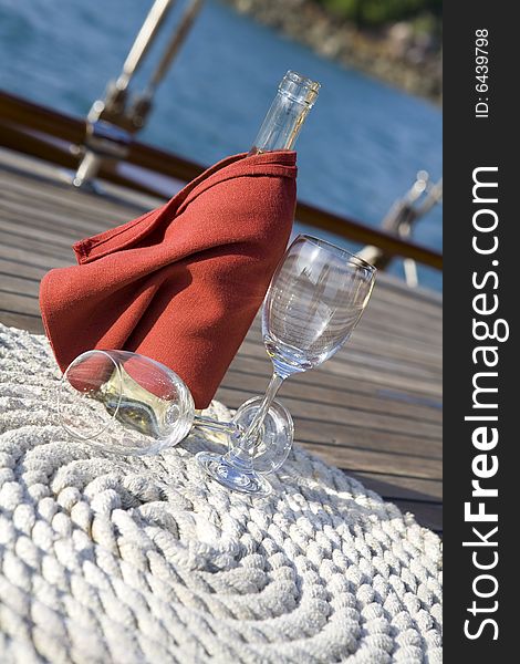 A bottle of wine and glasses on the wooden deck of a yacht. A bottle of wine and glasses on the wooden deck of a yacht