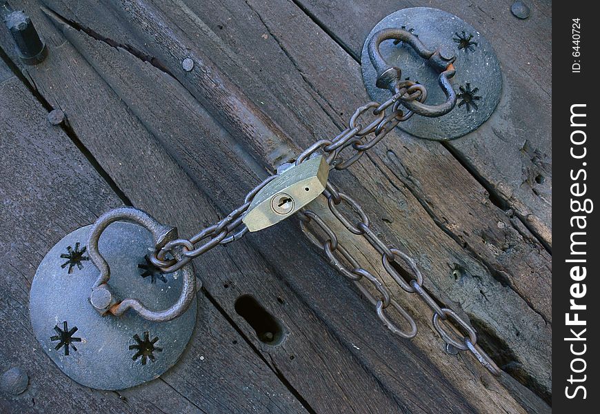 Old pig-iron chain with new lock on the old wood door. Old pig-iron chain with new lock on the old wood door