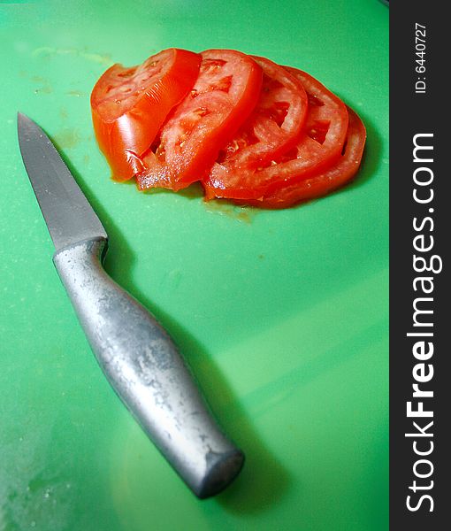 Knife laying on cutting mat after slicing tomatoes. Knife laying on cutting mat after slicing tomatoes