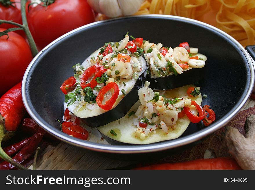 Some fresh aubergines with chili in a pan