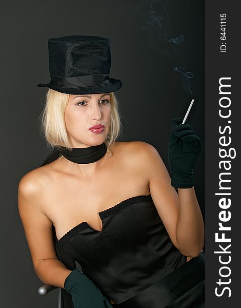 Young blonde woman in black hat keeps a cigarette thoughtfully. Young blonde woman in black hat keeps a cigarette thoughtfully.