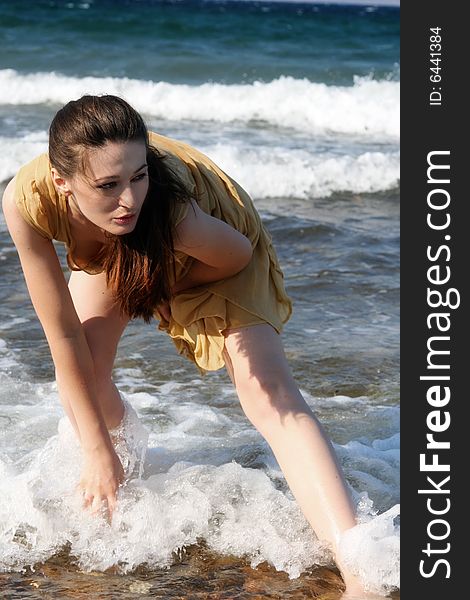 A brunette young beautiful woman wet by the sea water