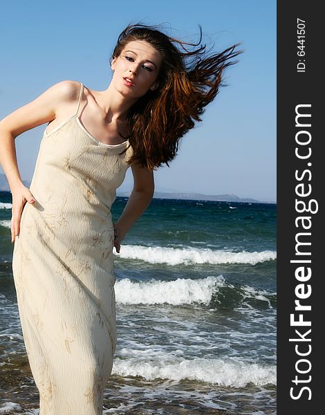 A young brunette beautiful woman by the windy seaside