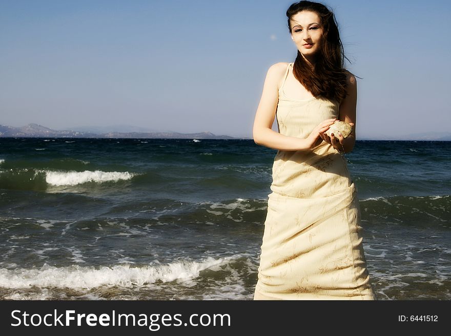 A young brunette beautiful woman by the windy seaside
