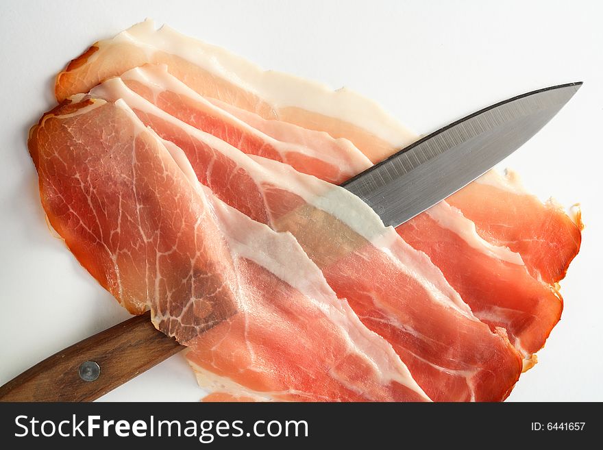 Slices of ham, pepper grains and knife. Slices of ham, pepper grains and knife