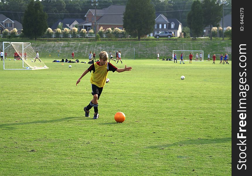 Boy Kicking A Ball On The Field.