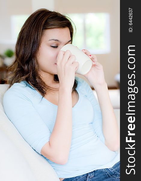 An attractive young woman drinking coffee at home. An attractive young woman drinking coffee at home