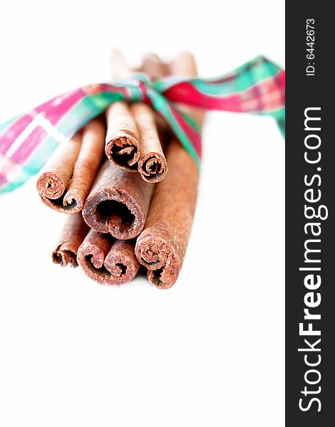 A high key image of cinnamon sticks with Christmas ribbon.
Copy space available.