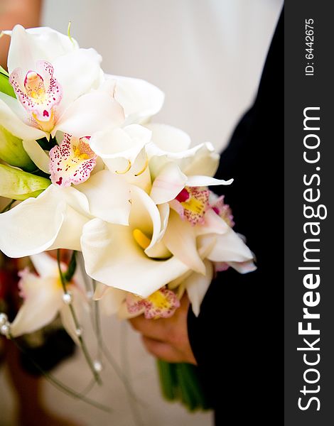 Groom holding a bouquet of orchids and lilies