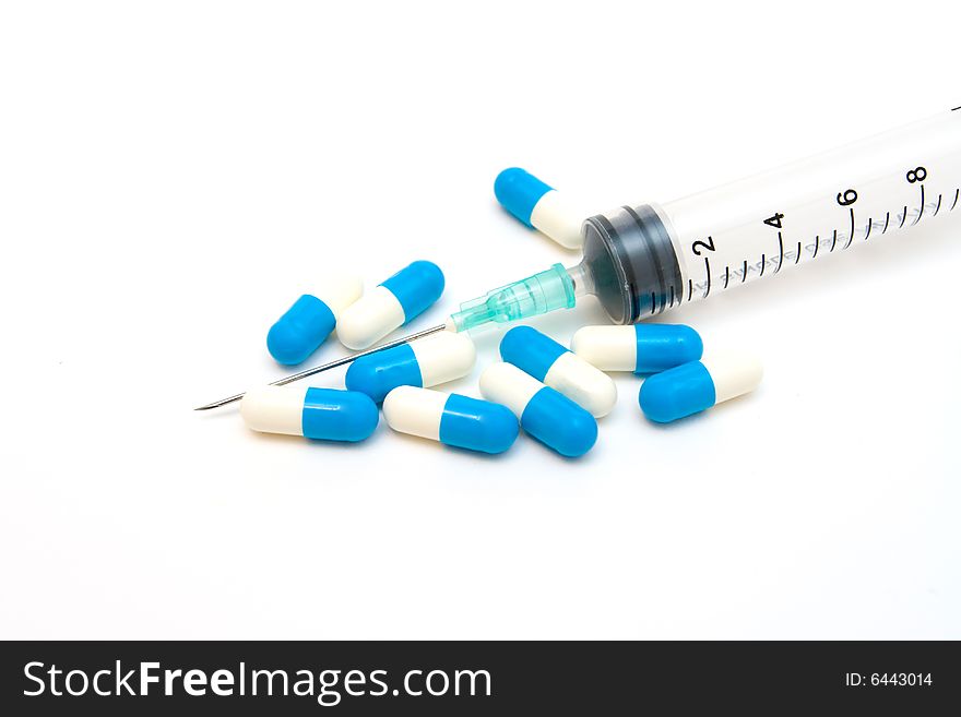 Pills and syringe on white background