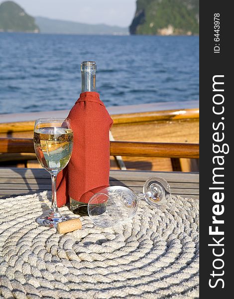 A bottle of wine and glasses on the deck of a yacht. A bottle of wine and glasses on the deck of a yacht
