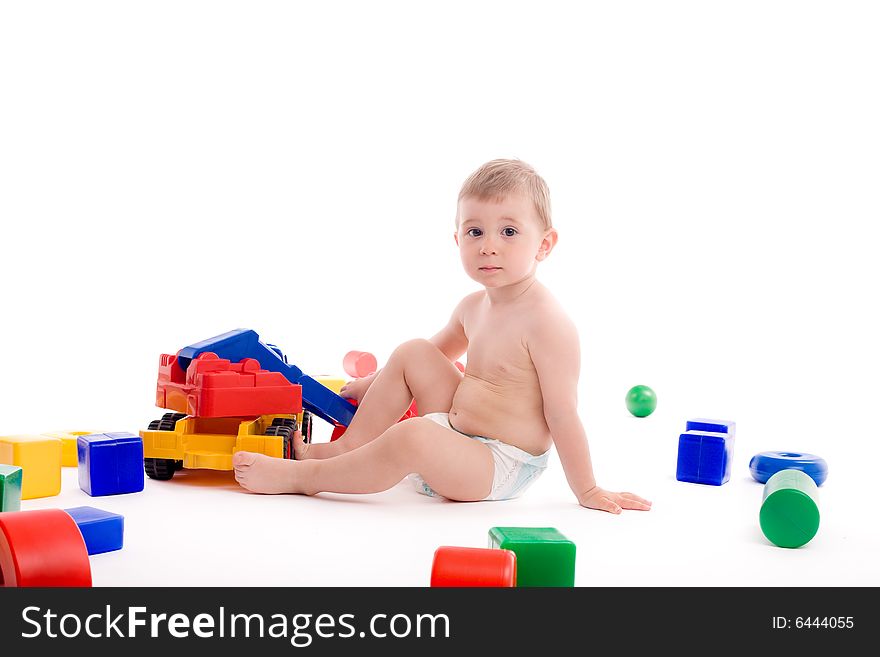 Little boy play with toys over white background with light shadows.