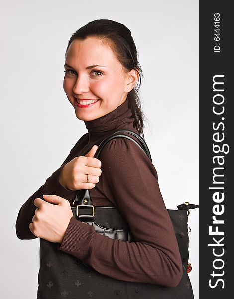Portrait of the charming girl with dark hair with bag on a light background