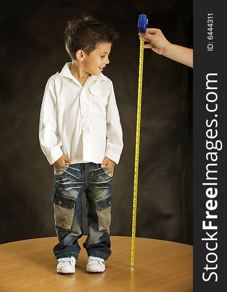 Boy is measured his increase by the tape-measure. Boy is measured his increase by the tape-measure