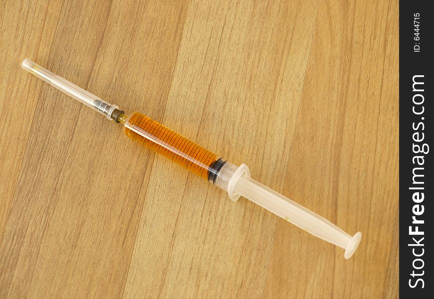 A syringe filled with orange fluid and the safety cap still on the needle