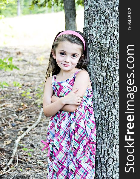 Young girl standing with arms folded next to a tree. Young girl standing with arms folded next to a tree.