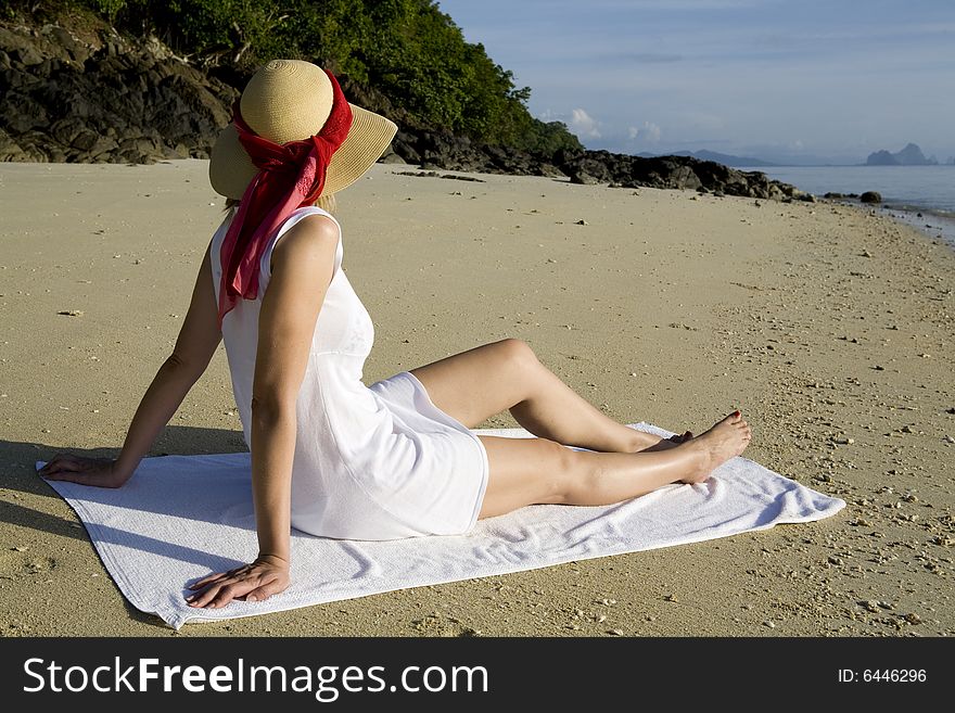 Woman with white dress and sun hat relaxing on the beach. Woman with white dress and sun hat relaxing on the beach