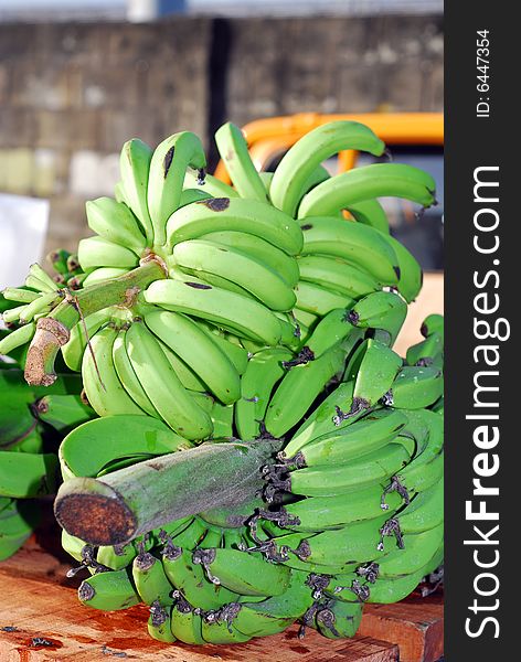 Fresh green bananas on stalk for sale at open tropical fruit market.