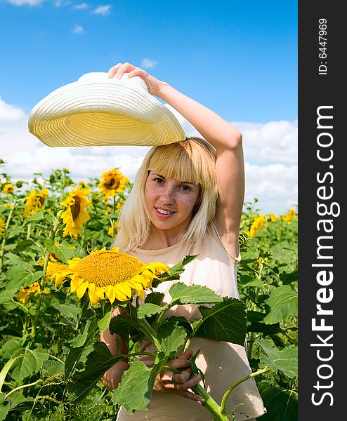 A girl holding a hat over a sunflower. A girl holding a hat over a sunflower